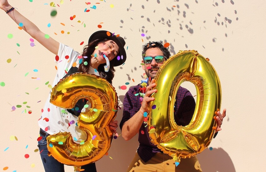 30th birthday ideas: couple holding golden number 3 and 0 balloons