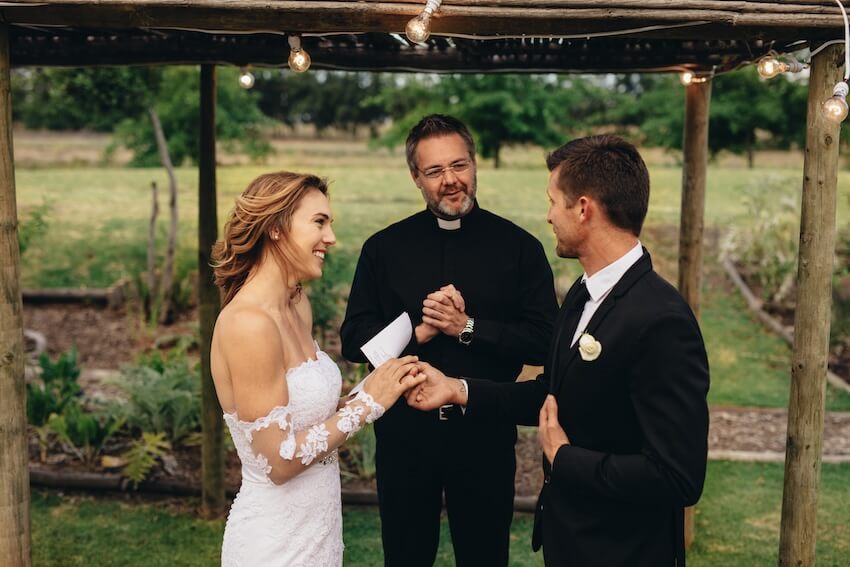 How to write wedding vows: couple holding hands while at their wedding
