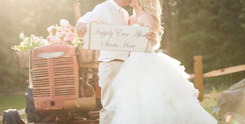 Couple kissing each other while holding a Happily Ever After Starts Here sign