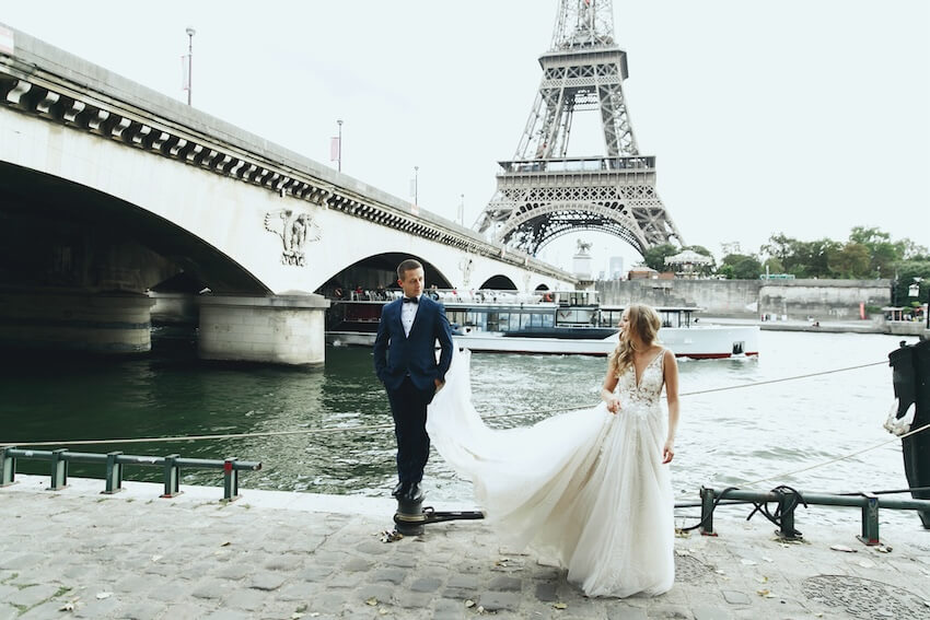 Destination wedding save the date: couple posing at the camera beside a river