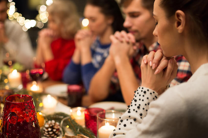 Religious Christmas cards: family praying together before eating