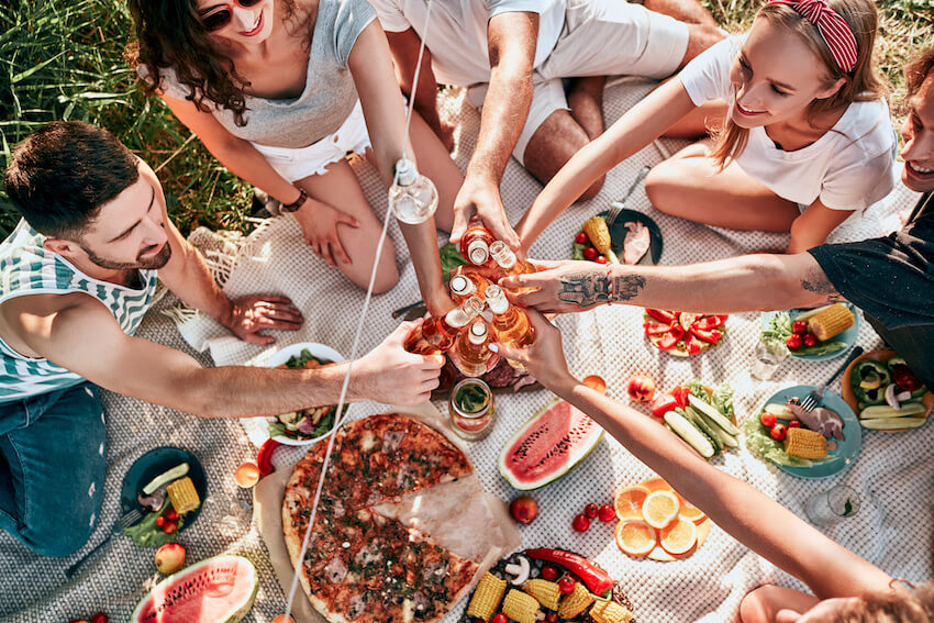 Birthday picnic ideas for adults: friends drinking and eating at a garden