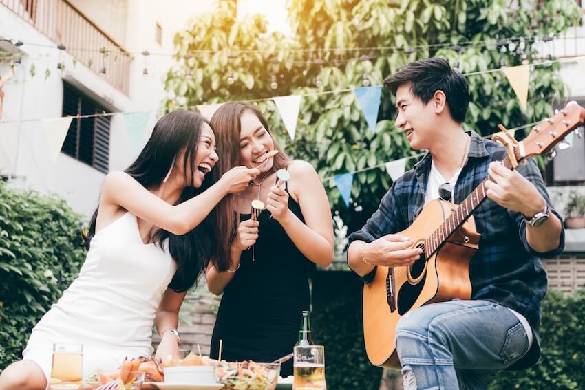 Graduation party checklist: friends eating outdoors while a man serenades them