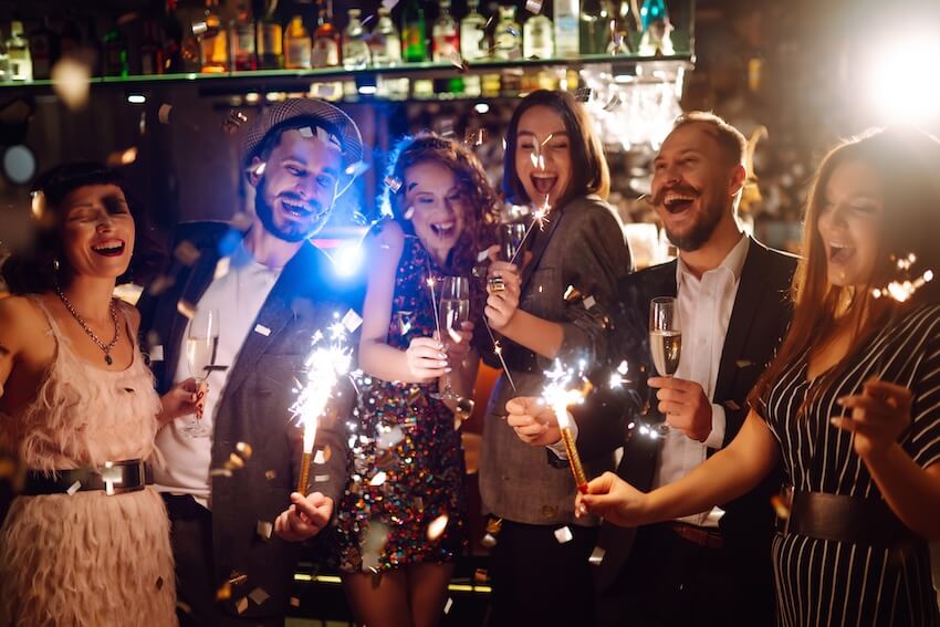 New Year's toast: friends holding some sparklers while drinking at a bar
