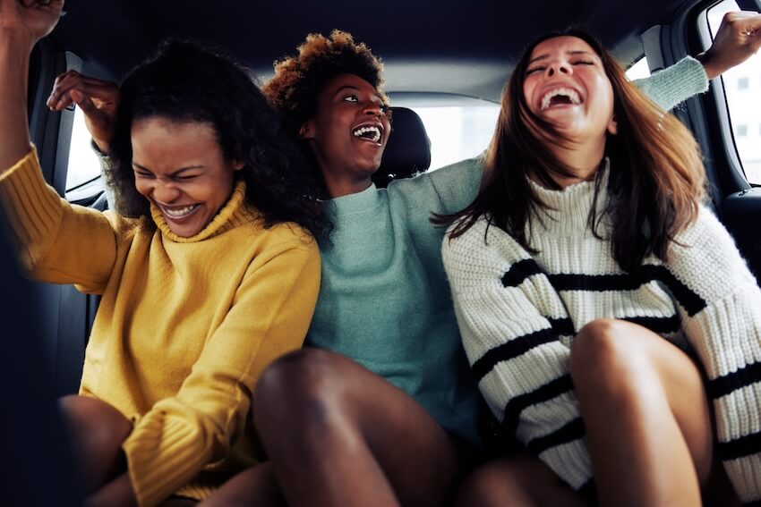 Girls weekend getaways: friends laughing while riding in a car