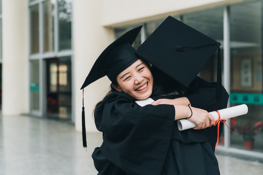 What to write in a graduation card: graduates happily hugging each other