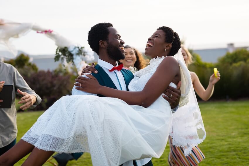 Wedding day timeline: groom carrying his bride