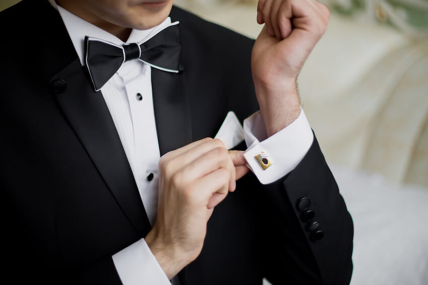 Wedding attire black tie: groom fixing his sleeve