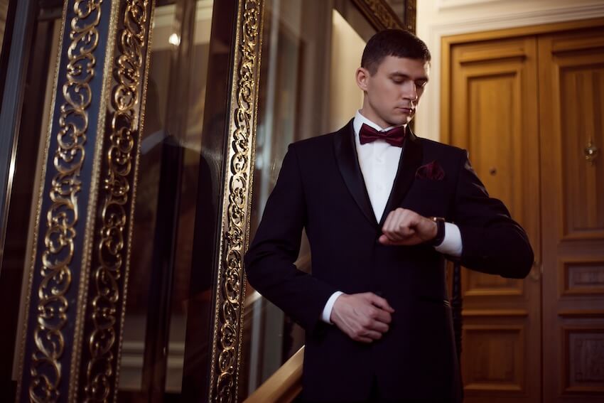 Black tie optional wedding: groom looking at his wristwatch