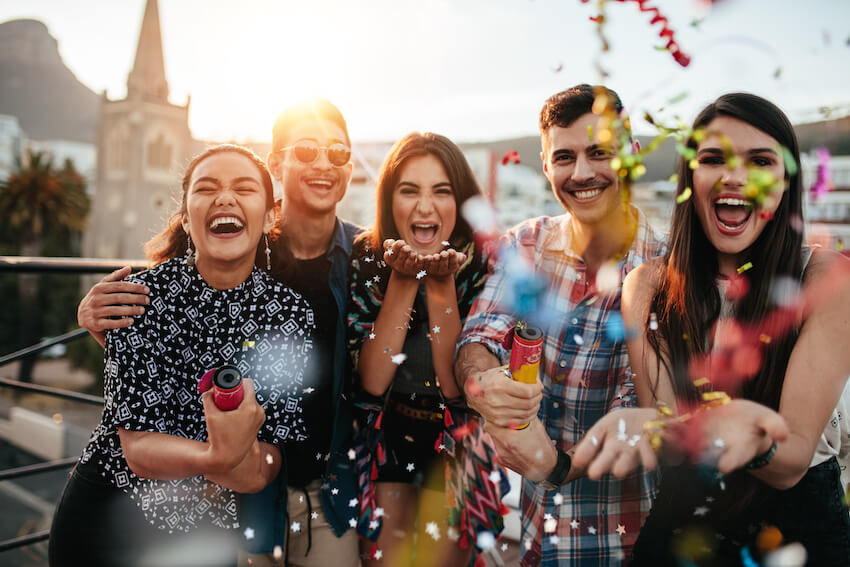 Outdoor birthday party ideas: group of friends happily celebrating and throwing some confetti