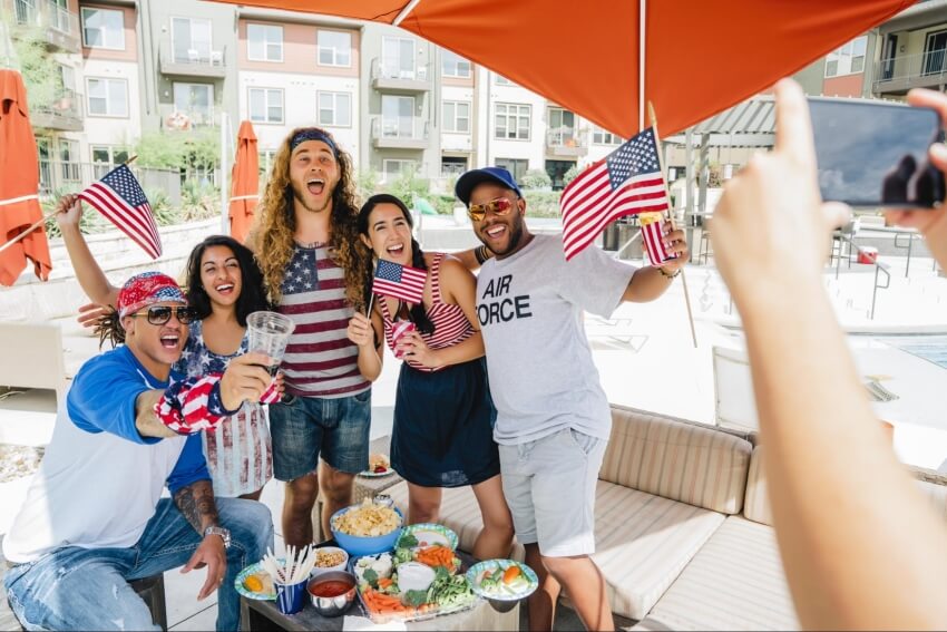 Group of friends holding American flags while posing for a picture