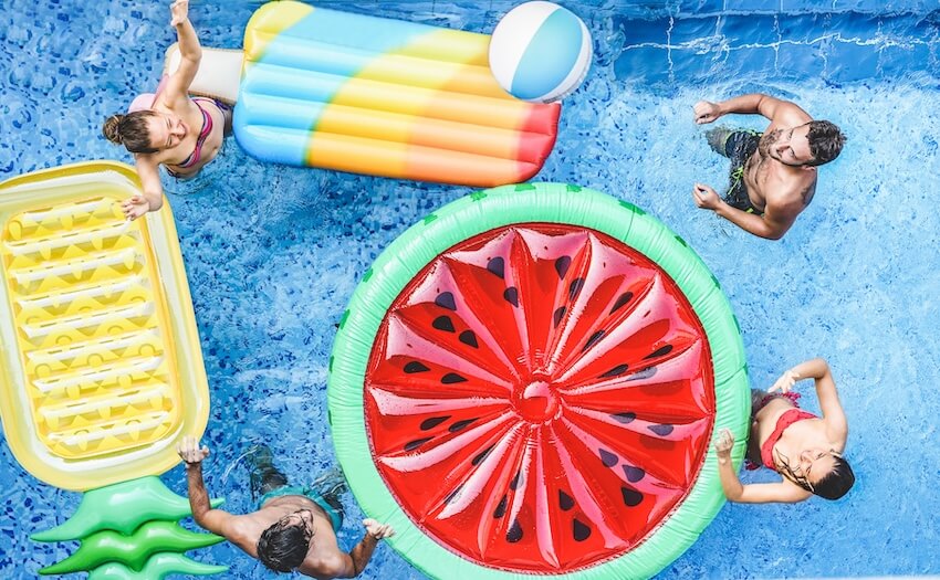Group of friends with colorful floaties in a pool