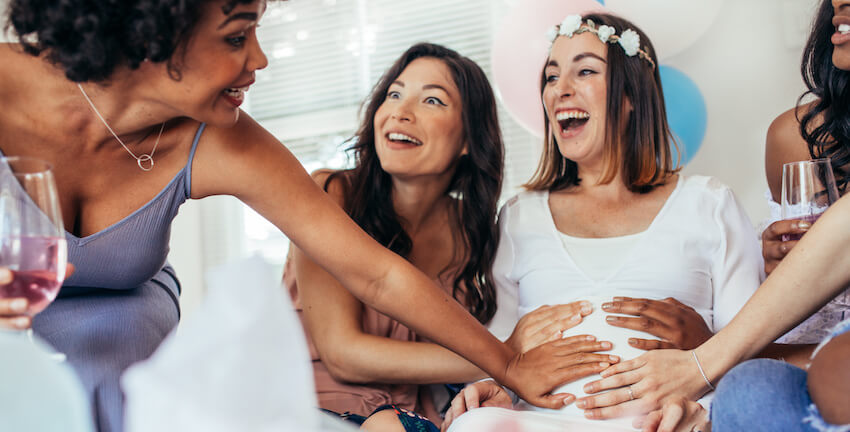How to plan a baby shower: group of people holding the belly of a pregnant woman