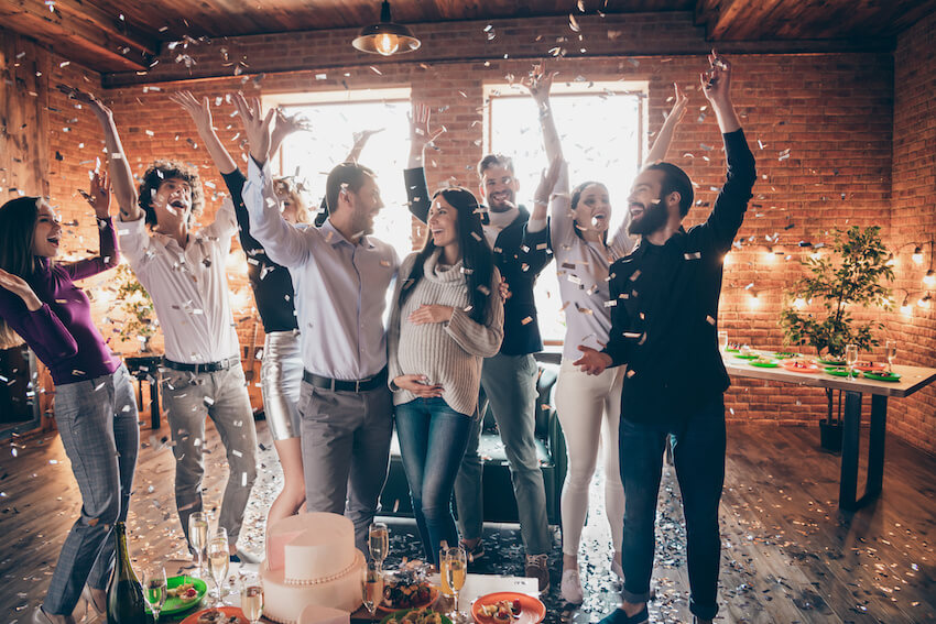 When to have a baby shower: group of people throwing confetti at a baby shower