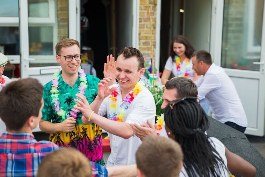 Luau party invitations: group of people wearing Hawaiian leis at a party