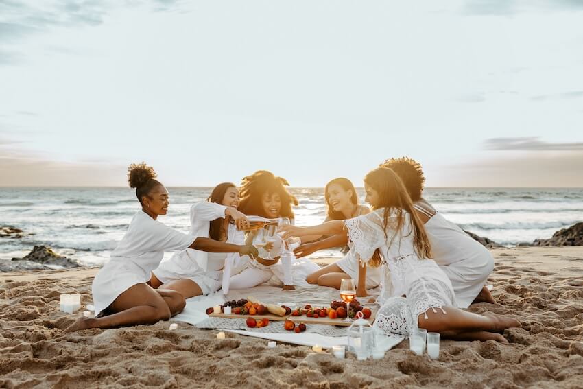 Bachelorette itinerary: group of women drinking at a beach