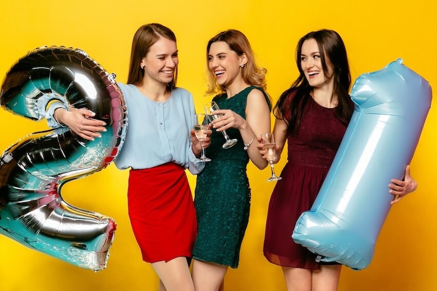 21st birthday theme ideas: group of women drinking while holding 2 balloons