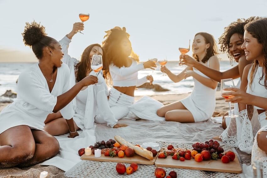 Girls weekend getaways: group of women having a picnic at a beach