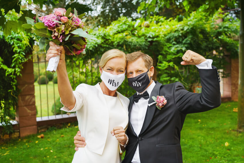 Happy bride and groom wearing masks on their wedding day