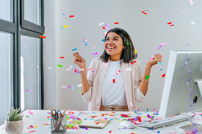 Congratulations on your work anniversary: happy employee catching confetti