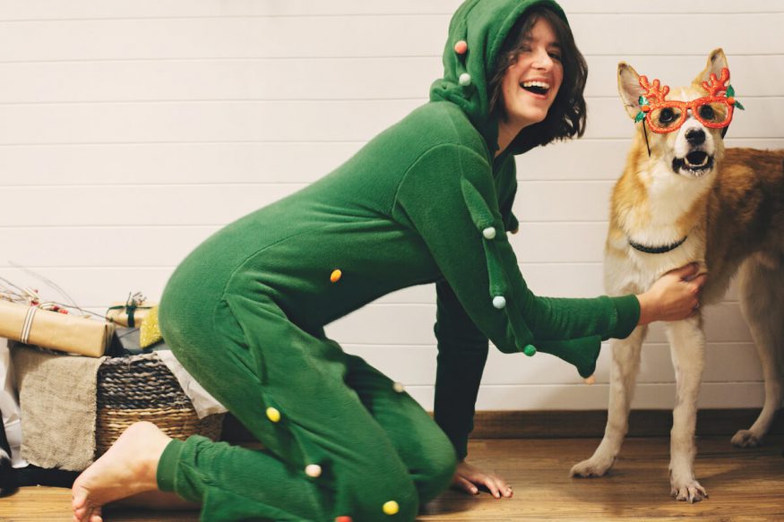 Woman in a Christmas onesie petting her dog