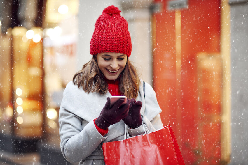 Christmas card text: happy woman using her phone during winter