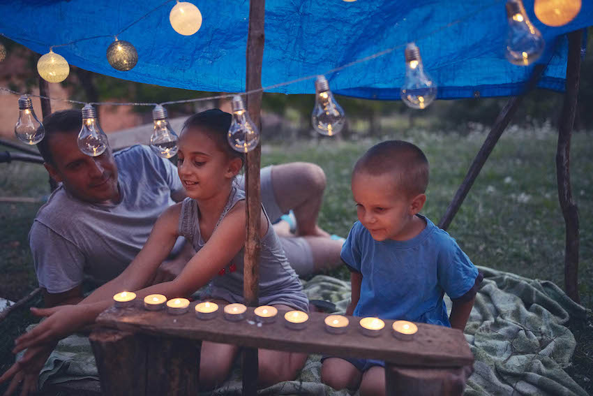 Quarantine birthday ideas for kids: Kids making a small tent with candles and lanterns