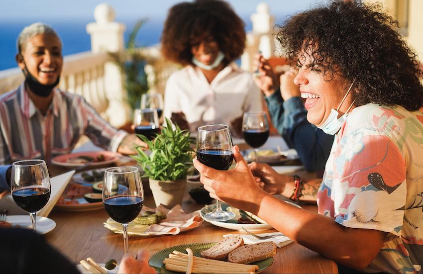 People eating and drinking red wine while wearing protective masks