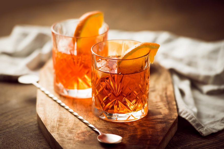 virtual happy hour: Two Scotch whisky cocktails and stirrer on top of a wooden serving board