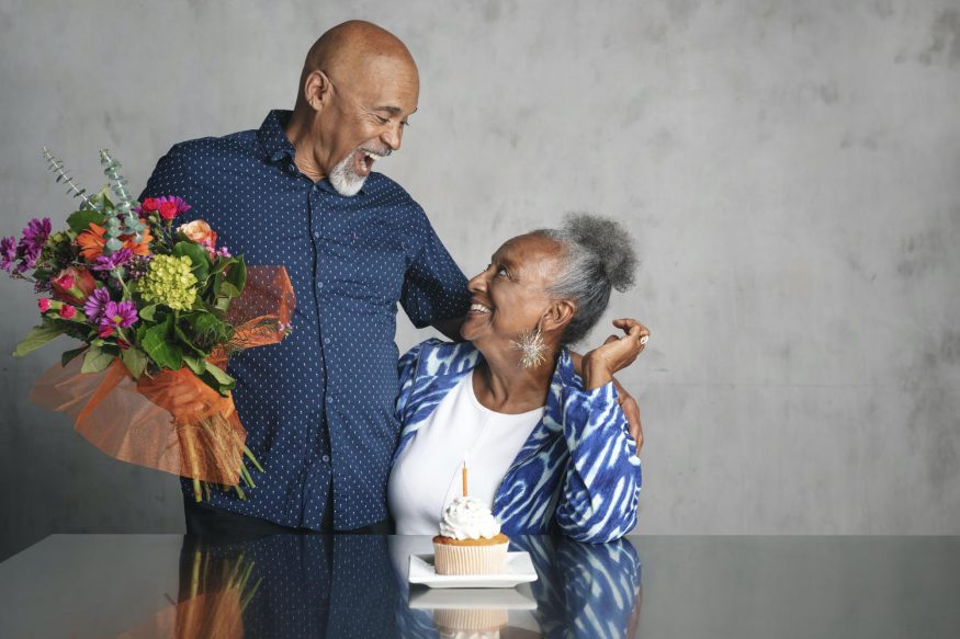 60th birthday party ideas: Man smiling at his wife while holding a bouquet of flowers