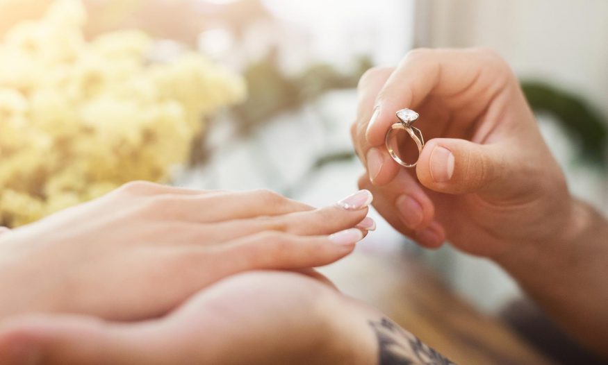 Man putting on an engagement ring on his new fiancée