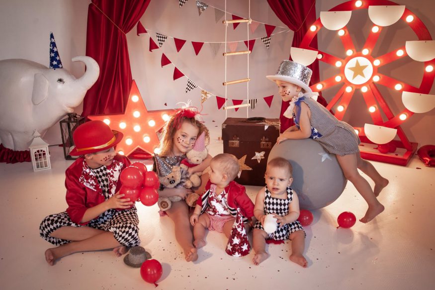 carnival theme party: A group of children in costumes with circus themed decorations around them