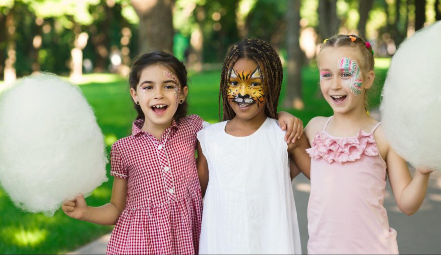 carnival theme party: Three girls smiling while holding cotton candy and face paint on