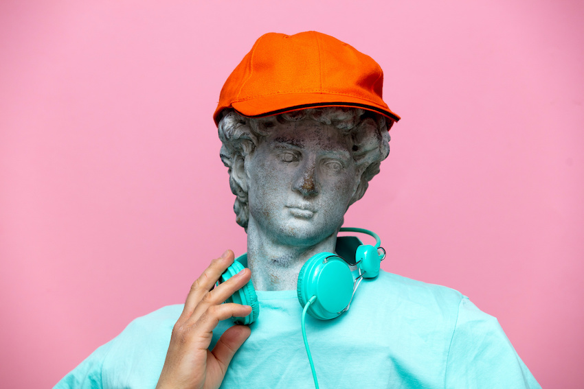 Antique bust of male in cap with headphones on pink background