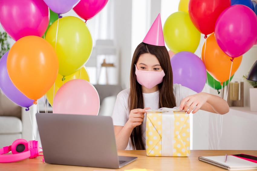 Quarantine birthday ideas for kids: Girl opening gift box infront of her laptop