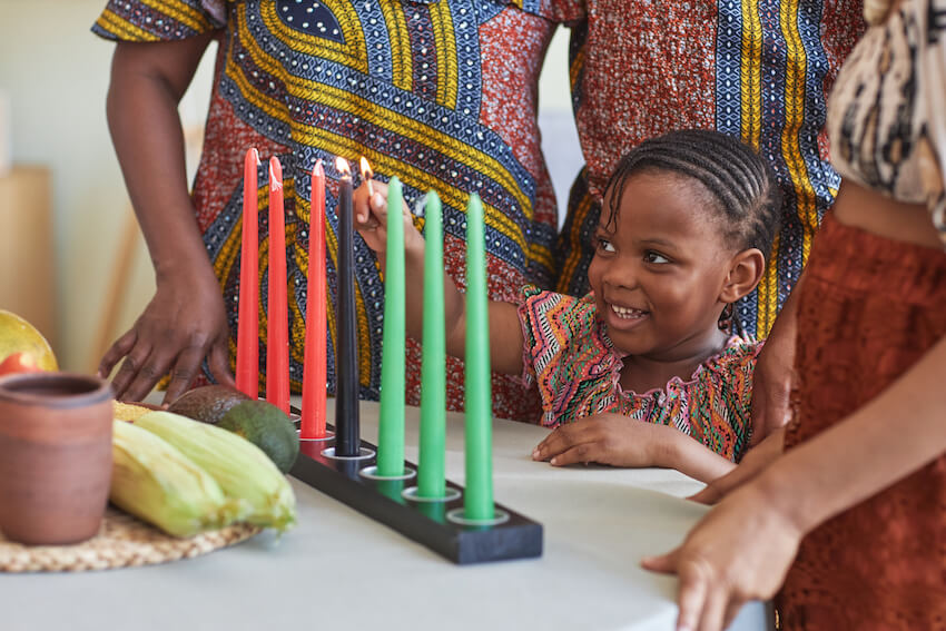Happy Kwanzaa: kid lighting up candles to celebrate Kwanzaa
