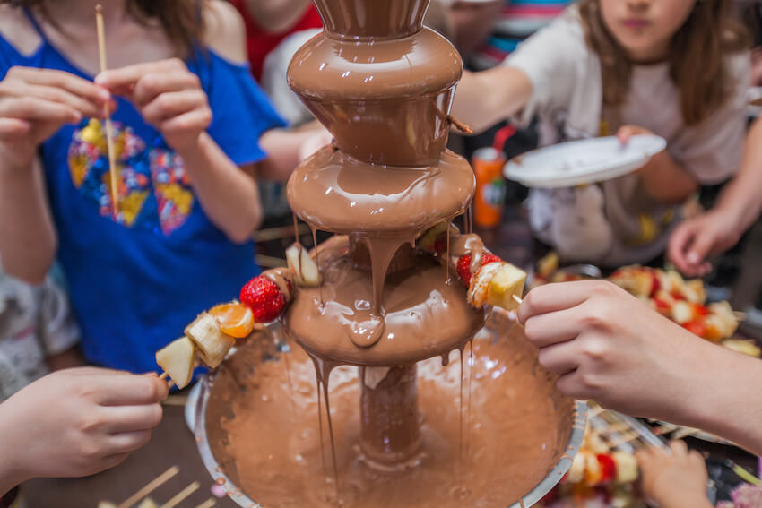 Kids dipping their food in a chocolate fountain