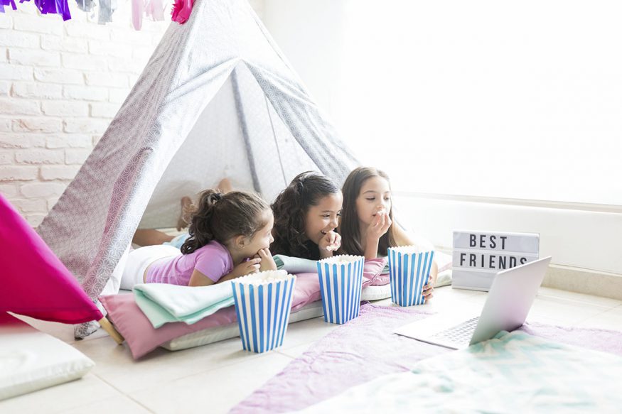 sleepover invitations: kids eating popcorn while watching a film in their tent