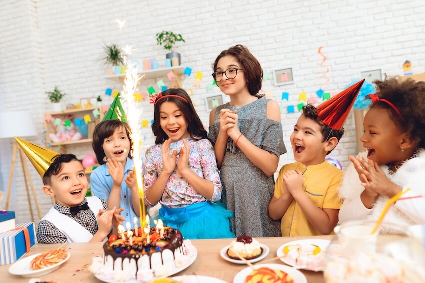 Candy themed birthday party: kids happily looking at a sparkler candle on a cake