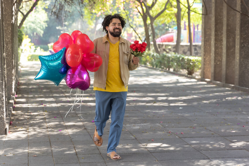 Happy late birthday: man carrying a bouquet of flowers and colorful balloons