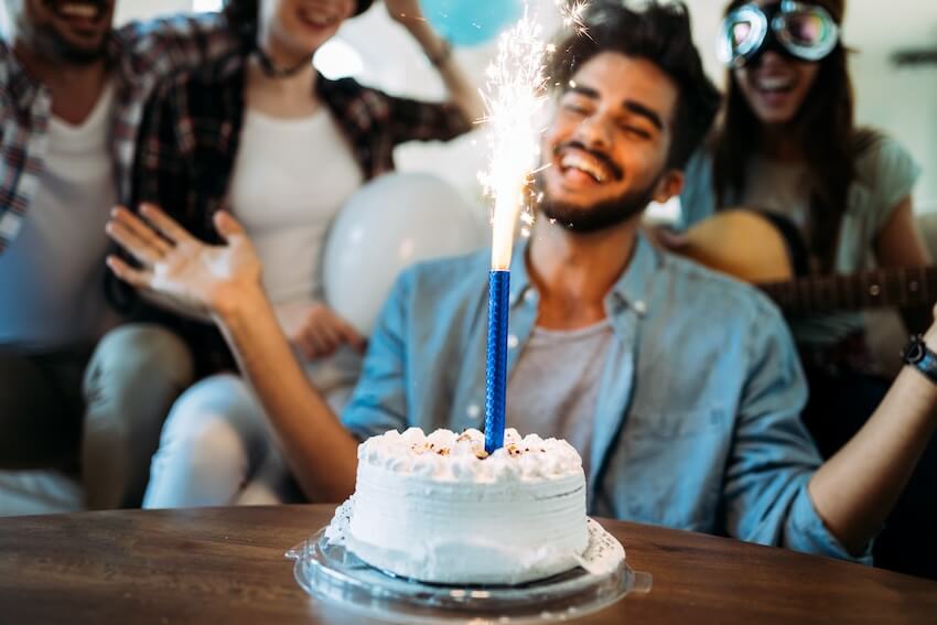 Men birthday invitation: man happily looking at the blue sparkle on his cake