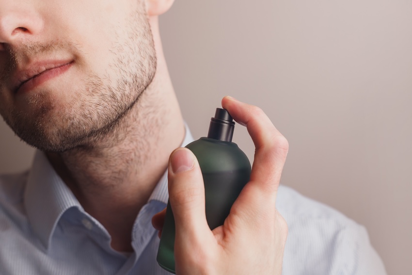 Man spraying perfume on his neck