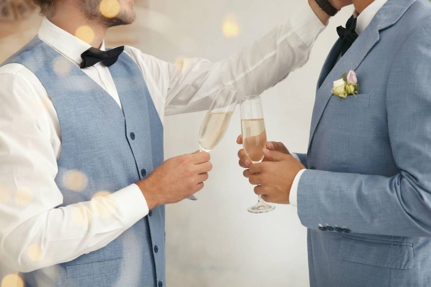 Wedding themes: Married couple in suits toasting with champagne
