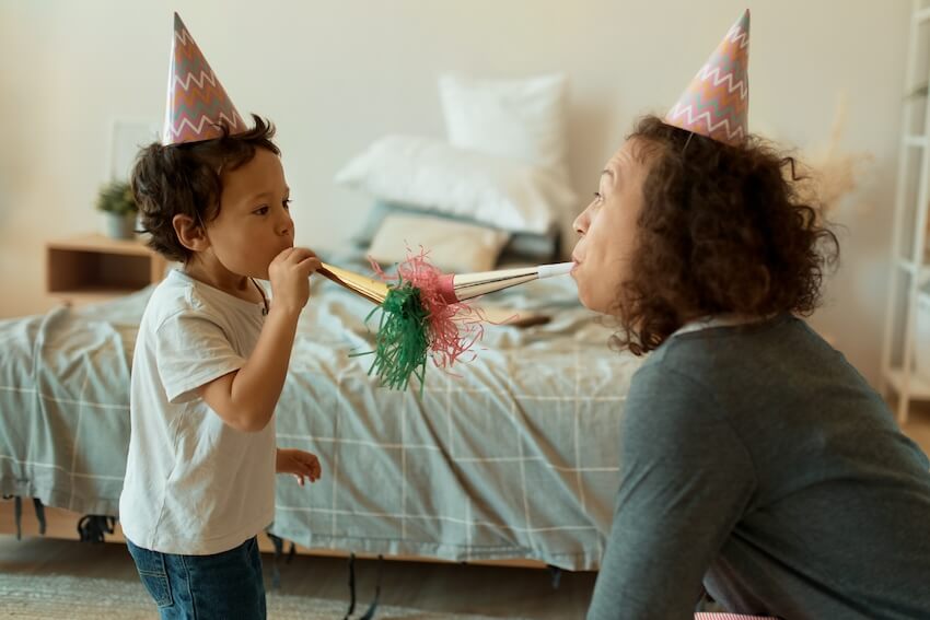Young wild and three birthday: mother and child blowing party horns