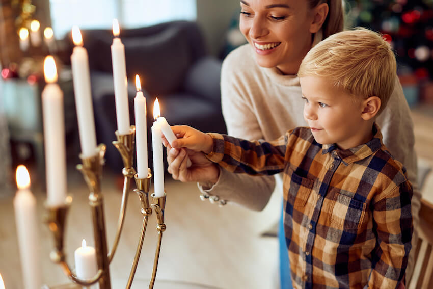 Hanukkah greetings: mother helping her son light up a candle