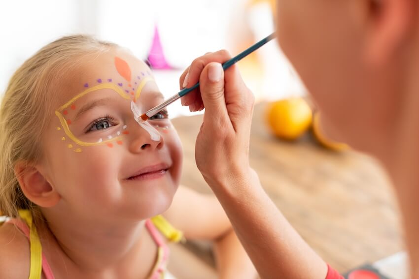 Mother painting her daughter's face