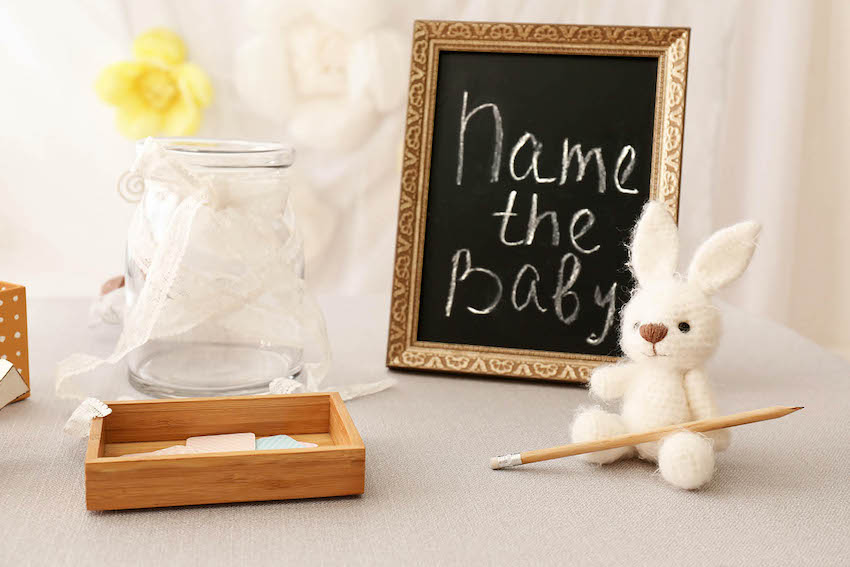Name the baby written on a frame and a small stuffed toy on a table