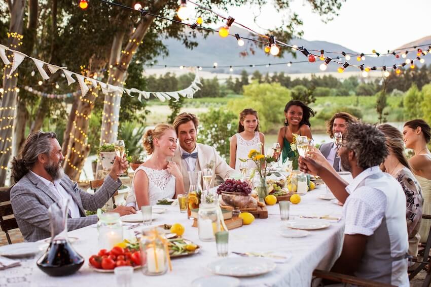 Newlywed couple and their guests eating outdoors
