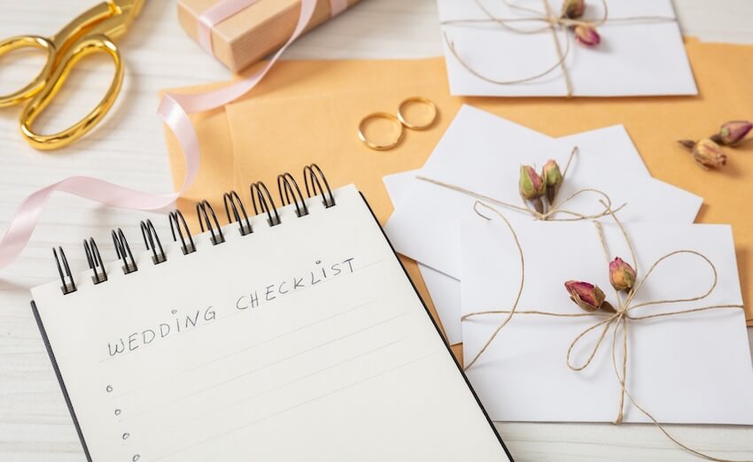 Wedding checklist: notebook, envelopes, and wedding rings on a table