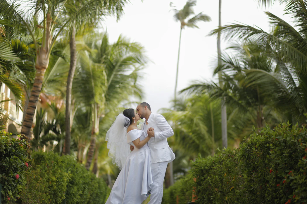 A bride and groom kiss in a tropical setting